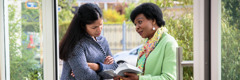 Svědkyně Jehovova ukazuje jedné ženě u ní doma verš z Bible