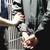 Dans une prison, un détenu menotté est escorté par un gardien