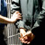 A handcuffed prisoner being escorted inside a prison.