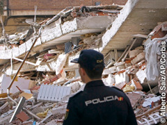Rescatista observando un edificio derrumbado por un terremoto