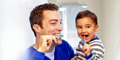 A father and his young son brushing their teeth