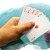 A person holds playing cards next to a stack of poker chips