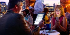 Un homme et sa femme dînant au restaurant utilisent leurs appareils électroniques au lieu de se parler