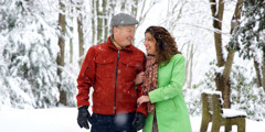 Et lykkelig gift par som går tur mens det snør