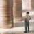 A man looks up at very tall stacks of coins