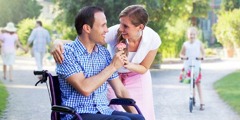 A man in a wheelchair gives his wife a flower