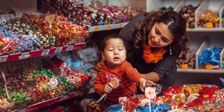 A mother says no as her little boy tries to pick out candy in a store
