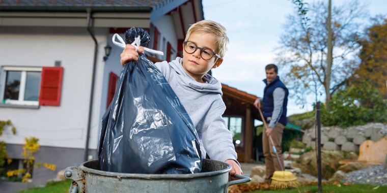 A boy puts trash in a bin