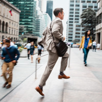 Un hombre de negocios corriendo hacia la entrada de un edificio de oficinas