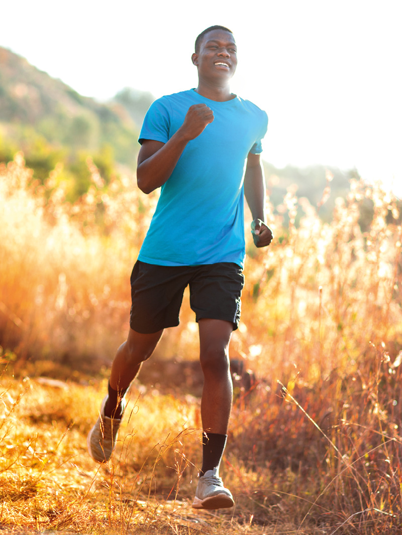 Un joven sonriente corriendo por el campo