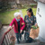 An Indian woman helping an older Caucasian woman up the stairs with her groceries.