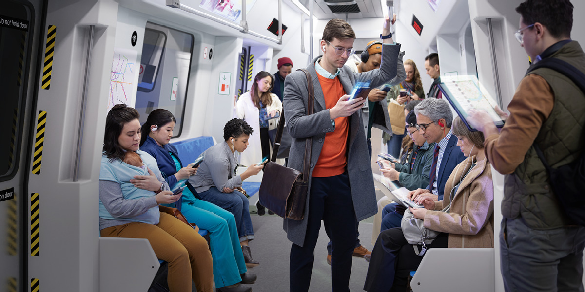 Personas en un tren mirando sus dispositivos electrónicos.