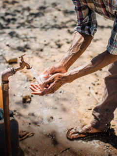 Een man die zijn handen buiten wast met water en zeep.
