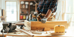 Një marangoz ngul një gozhdë në një copë druri.