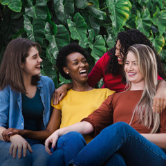Vrouwen van verschillende rassen lachen en genieten van elkaars gezelschap.