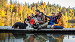 Родители со своите две деца седат покрај езеро и уживаат во природата.