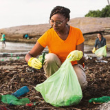 Eine Gruppe Freiwilliger sammelt an einem Strand Müll auf.