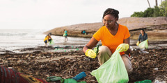 Група хора събират боклук на морски бряг.