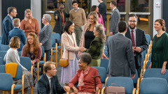 Inside a Kingdom Hall of Jehovah’s Witnesses before a congregation meeting. People of various ages and backgrounds warmly greet and converse with one another.