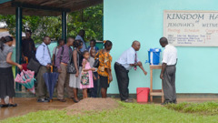 Jehovah’s Witnesses waiting patiently in line at a handwashing station before entering a Kingdom Hall.