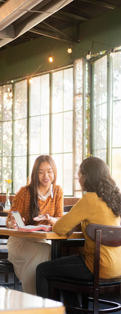 Una testigo de Jehová le da clases de la Biblia a una mujer en una cafetería.