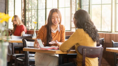 Una testigo de Jehová le da clases de la Biblia a una mujer en una cafetería.