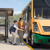 A mother and her young son helping an elderly woman to exit a bus.