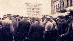 Jehovah’s Witnesses facing an angry and threatening mob. They are being forced to carry a sign that reads: “We are traitors, we did not vote.”