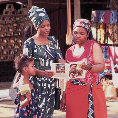 One of Jehovah’s Witnesses and her little girl preach to a woman at a shop