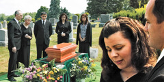 Grieving people around a small casket in a graveyard
