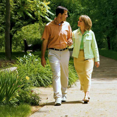 Un matrimonio caminando alegres en un parque brazo con brazo