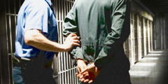 A brother wearing handcuffs and being escorted to a prison cell by a guard.