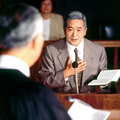 Un hermano con una Biblia abierta en sus manos defendiendo la verdad ante un juez en un tribunal.