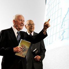 Brothers John Barr and Theodore Jaracz of the Governing Body looking at a world map. Brother Barr holds the book “‘Bearing Thorough Witness’ About God’s Kingdom.”