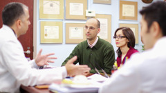 Doctors talking to a patient and his wife in an office.