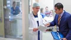 Um representante da Comissão de Ligação com Hospitais falando com um médico.