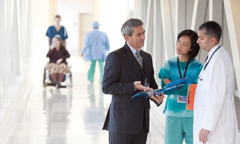 A Hospital Liaison Committee representative talks with two clinicians at a hospital