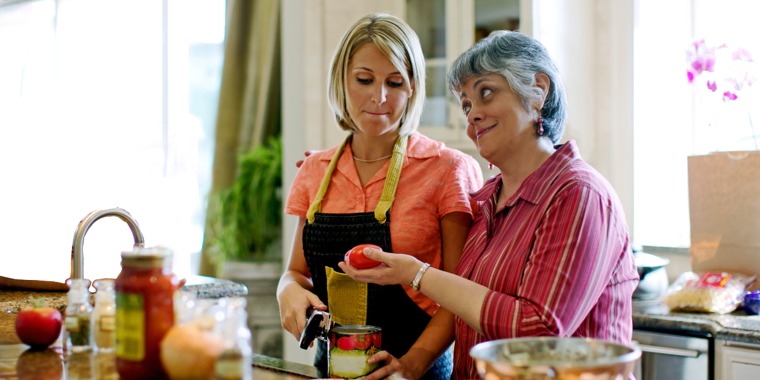A mother-in-law looks disapprovingly at the cooking methods of her daughter-in-law