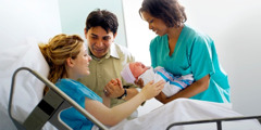 A nurse brings parents their newborn baby