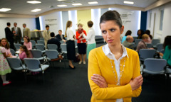 Een zuster in een Koninkrijkszaal ziet er gekwetst en boos uit terwijl ze kijkt naar een andere zuster