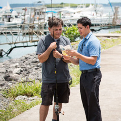 Een broeder gebruikt een traktaat om in een haven tot een visser te prediken