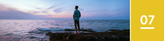 Lesson 7. A man stands on a rocky shore and looks across the ocean at twilight.