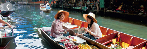 Ç. Një Dëshmitare e Jehovait po i predikon një gruaje në një treg mbi ujë në Tajlandë.