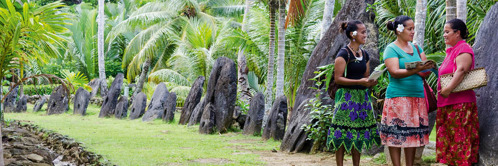 E. Dvě svědkyně Jehovovy mluví se ženou před obřími kamennými kotouči na ostrově Yap