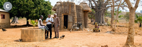 C. Two of Jehovah’s Witnesses preaching to a man in a rural village in Benin.