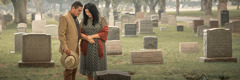 A couple grieving in a cemetery.