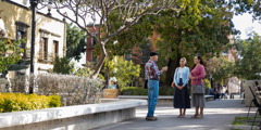 A man conversing with two sisters in a public park.