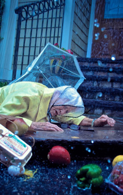 An elderly woman that has fallen and dropped all her groceries