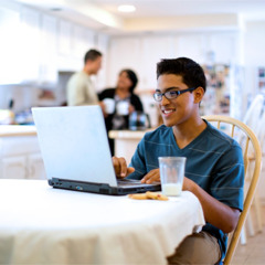 Млад мъж спокойно гледа компютъра си на място, на което всеки може да го вижда