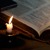 An open Bible illuminated by candlelight